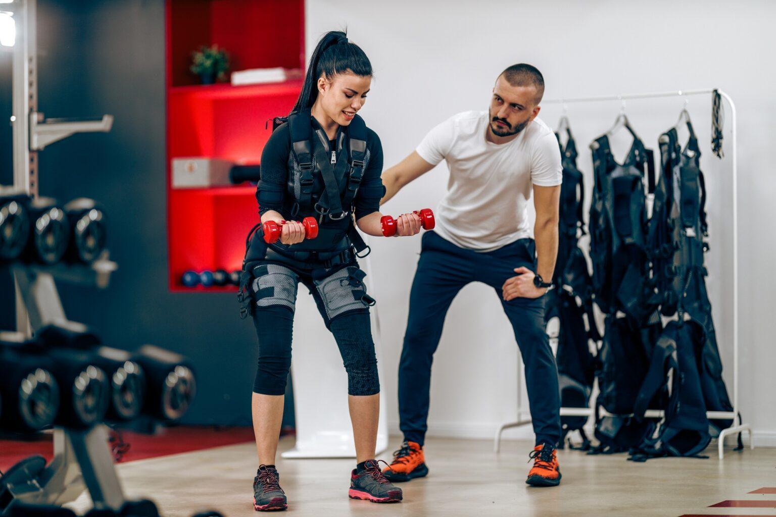 Woman Doing EMS Workout With Personal Trainer In The Gym